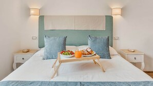 Een bed met een ontbijtbakje, twee kussens en nachtkastjes.