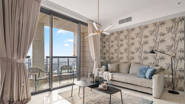 A modern living room with a sofa, coffee table, and a view of the city through large windows.