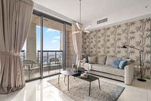 Un moderno salón con sofá, mesa de centro y vistas a la ciudad a través de amplias ventanas.