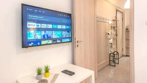Een flatscreen-tv aan de muur met een streamingdienst interface en diverse apps en content.