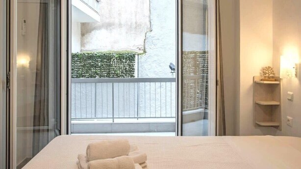Ein Schlafzimmer mit einem Bett, einer Schiebetür zu einem Balkon und einer kleinen Ablage mit einem dekorativen Gegenstand.