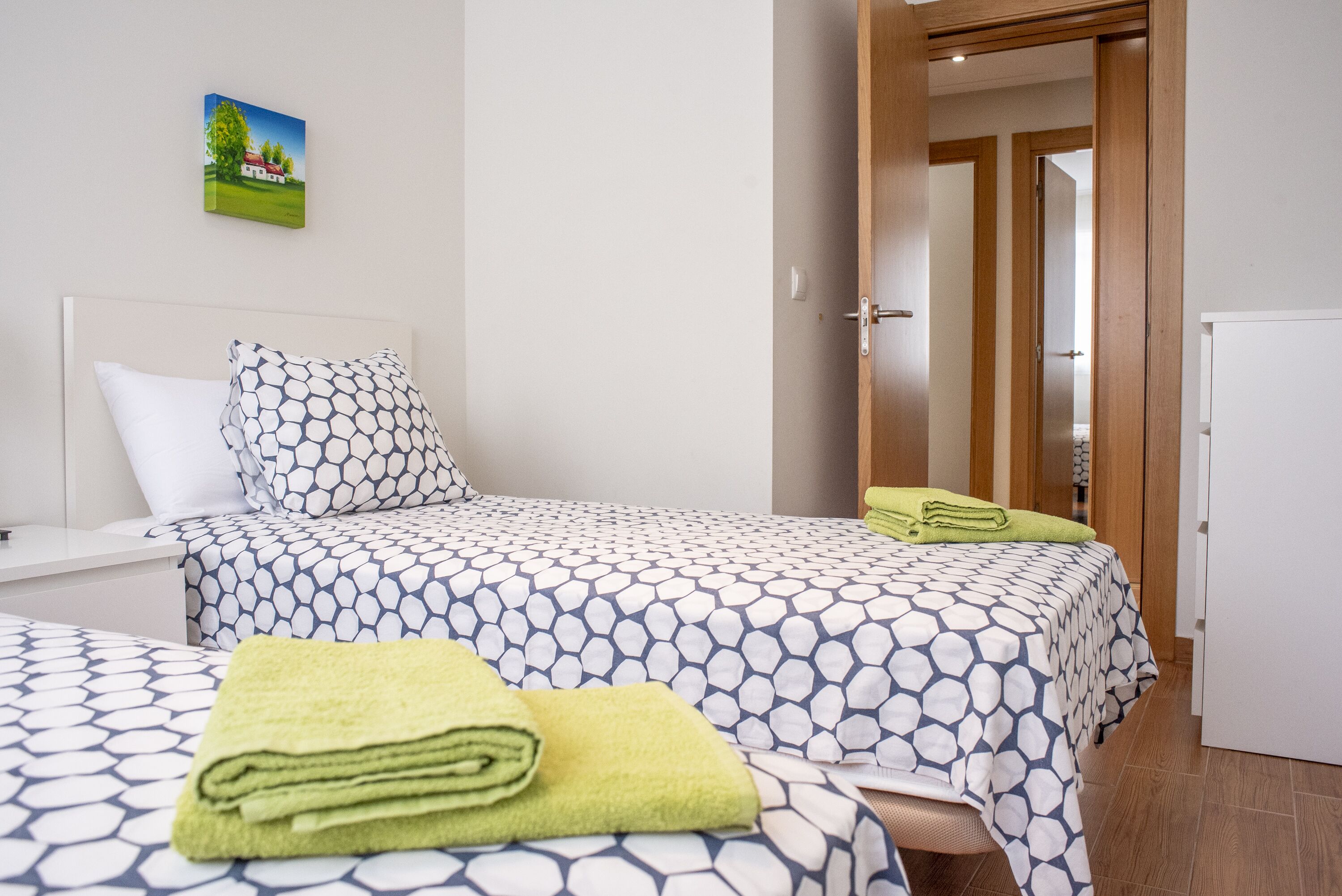 A hotel room with two beds, a wooden door, and a small white cabinet.