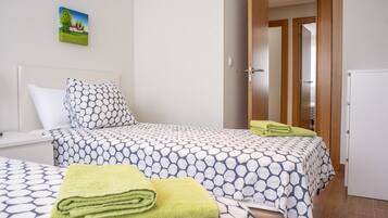A hotel room with two beds, a wooden door, and a small white cabinet.