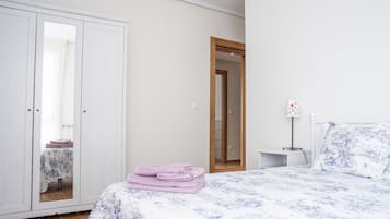 A bedroom with a bed, a wardrobe, a nightstand, and a mirror.