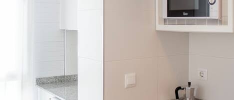 A compact kitchen with a washing machine, a microwave, and a dishwasher.