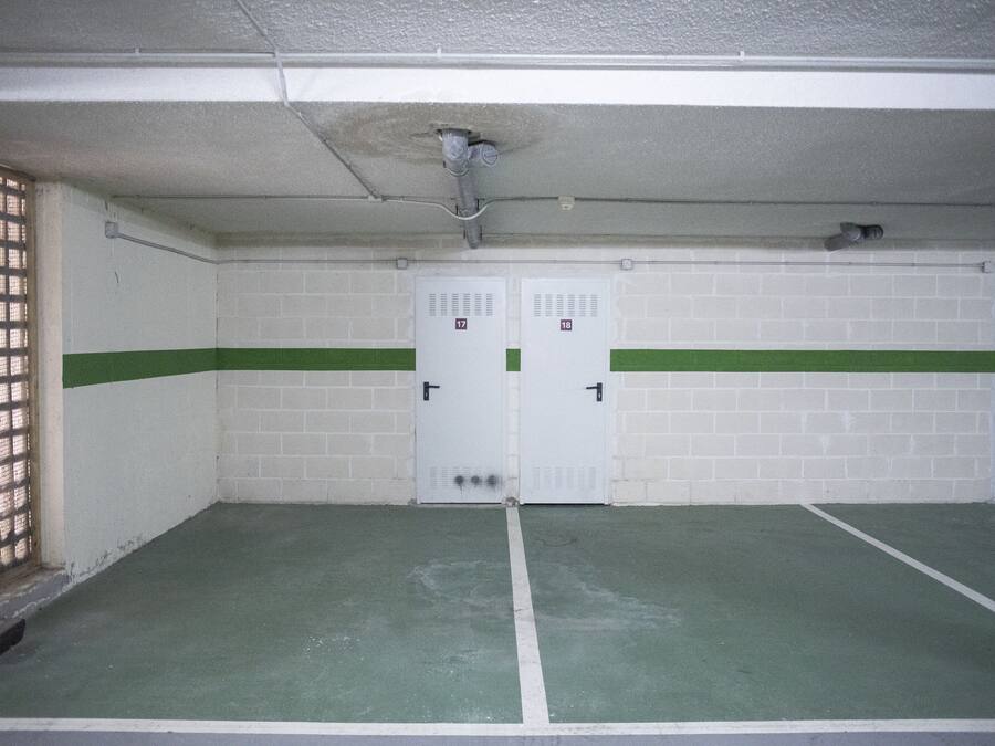 A parking garage with three white doors marked 17, 18, and 19.