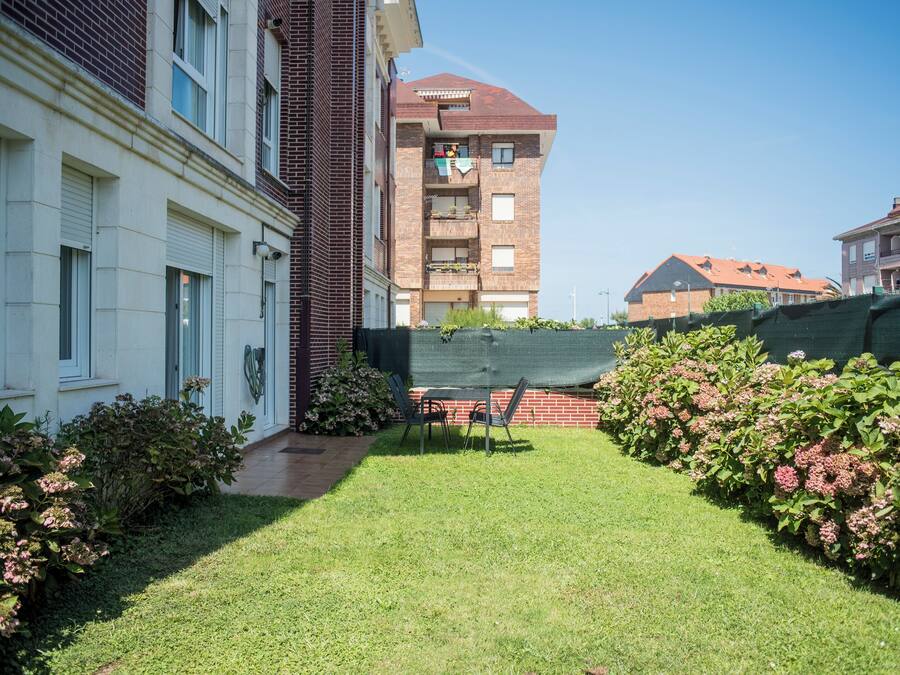 Un patio con césped, una mesa y sillas, y un edificio de ladrillo con varios balcones.