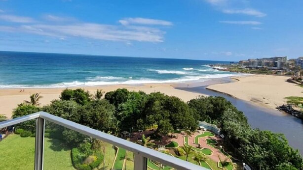 Vista costera desde un balcón con vista a la playa y el océano.
