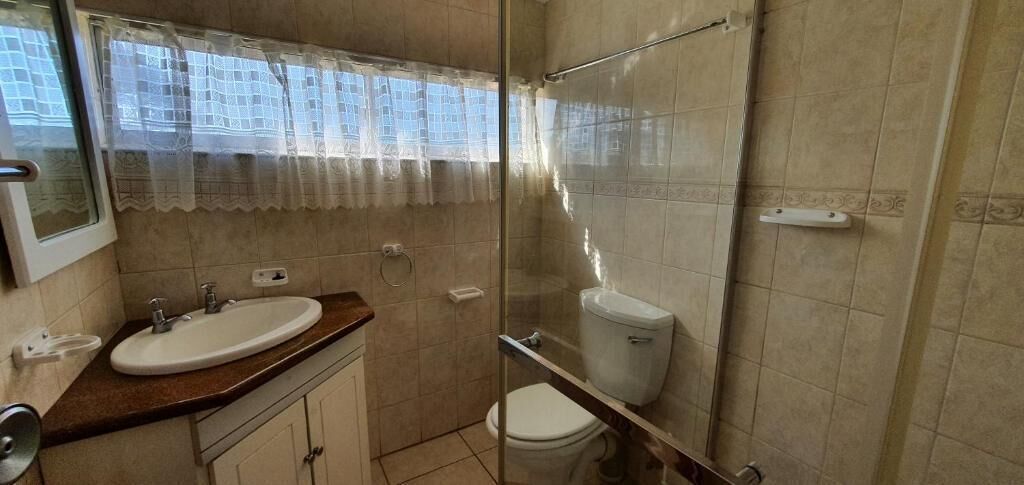 A bathroom with a glass shower enclosure, a sink, and a toilet.