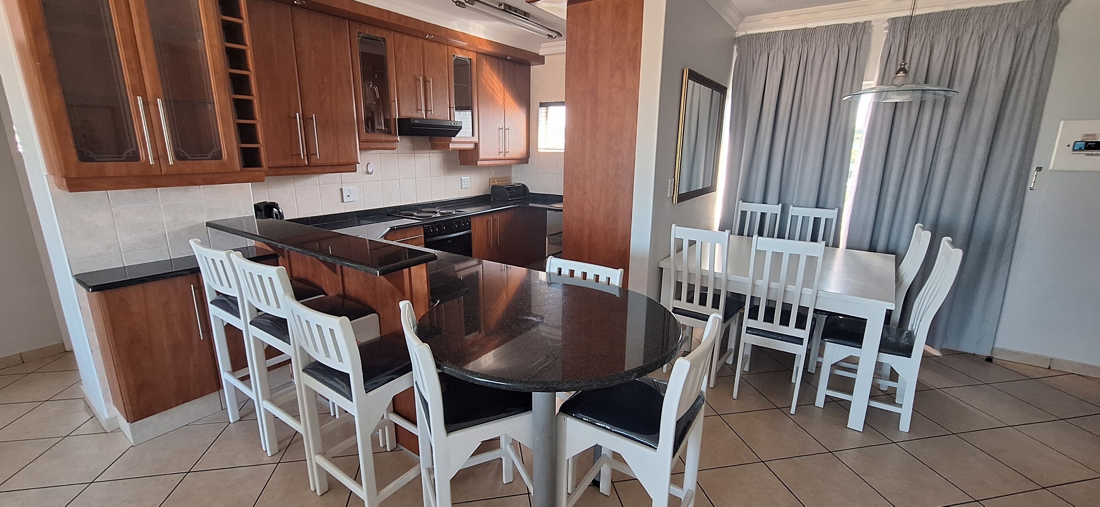 A kitchen with wooden cabinets, a stove, and a dining area with a round table and white chairs.