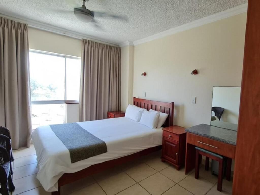 Une chambre d’hôtel comprenant un lit, des tables de chevet, un bureau et une chaise.