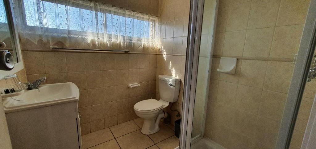 A bathroom with a toilet, sink, and shower area.