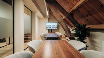 Une salle de conférence avec une table en bois, des chaises, un téléviseur et un escalier.