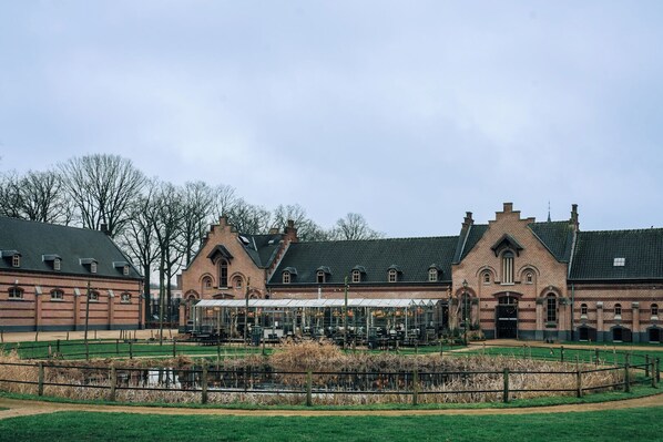 A historic building with a covered outdoor seating area and a fenced garden.