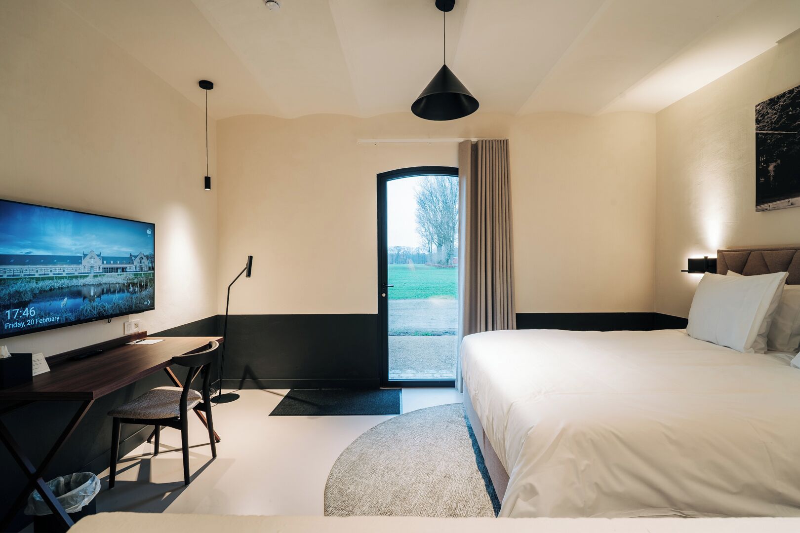 Une chambre d’hôtel moderne équipée d’un lit, d’un bureau, d’une télévision et offrant une vue sur l’extérieur.