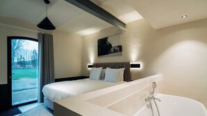 Ein modernes Hotelzimmer mit einem großen Bett, einer Badewanne und Blick ins Freie.