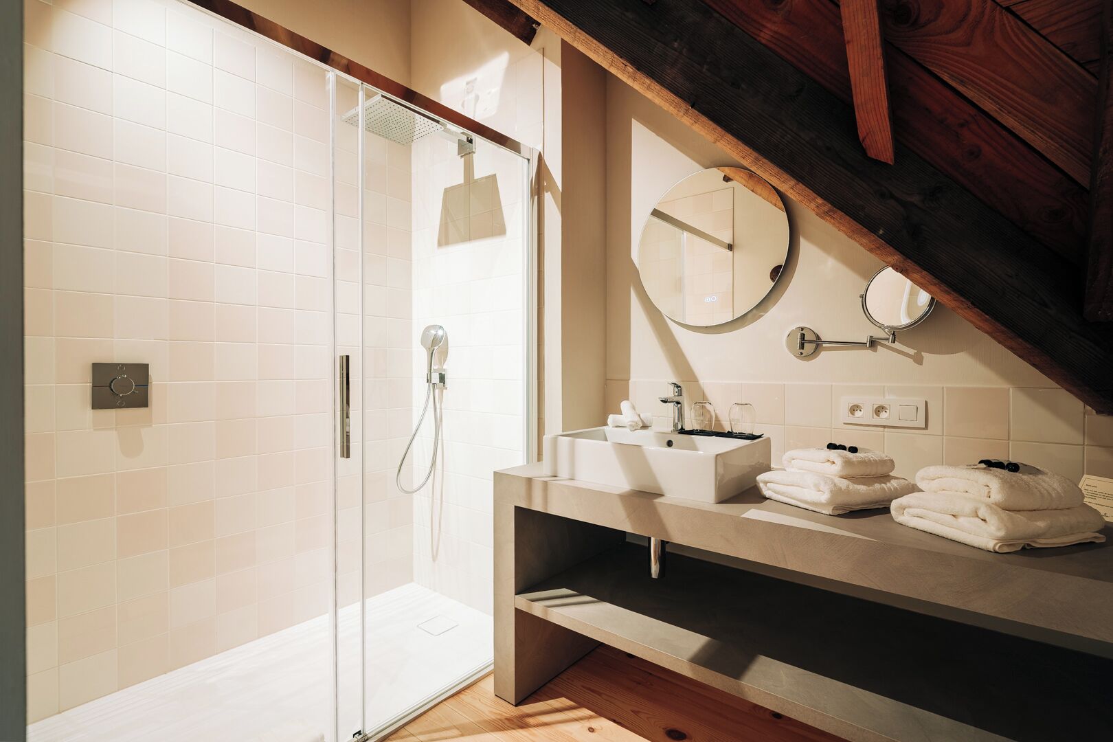A modern bathroom with a glass shower enclosure, a vanity with a mirror, and neatly folded towels.