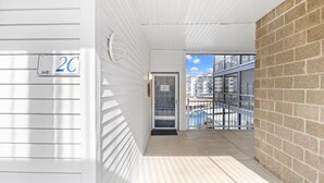 A corridor with a door, a balcony with a railing, and a view of buildings. - Heavenly Hideaway - 2 Pools, Hot Tub, & More! (Lake Ozark)