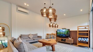 A modern living room with a sofa, coffee table, TV, and decorative lighting. - Villa Aura Canggu (Canggu)