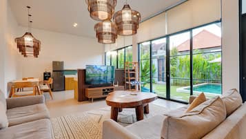 Una sala de estar moderna con un televisor grande, sofá y comedor.