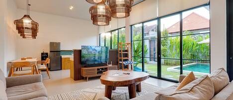 A modern living room with a large TV, sofa, and dining area.