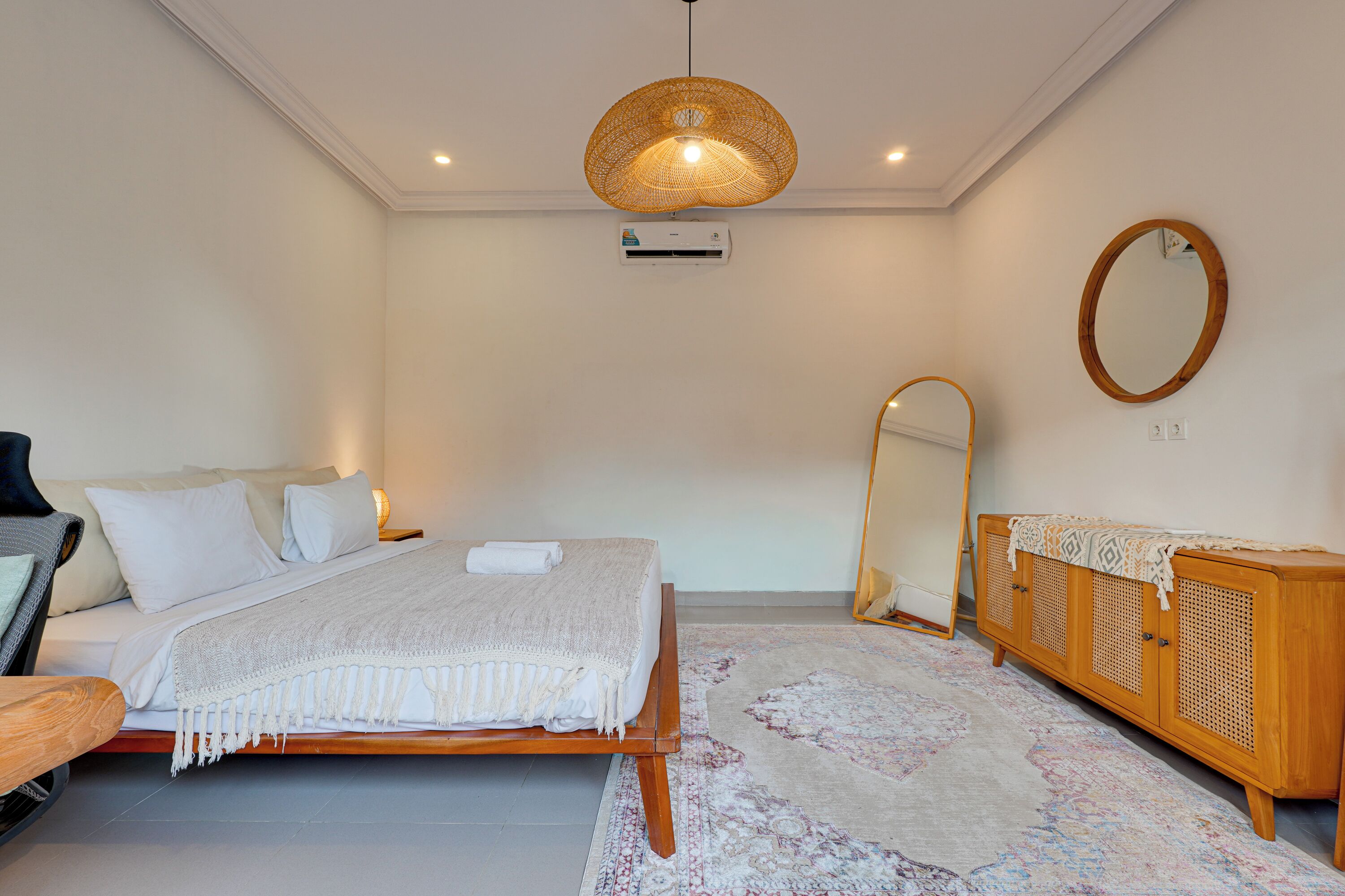 A bedroom with a bed, bedside table, mirror, wardrobe, and a hanging light fixture.