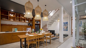 Une cuisine moderne avec des meubles en bois, un coin repas avec une table et des chaises en bois, et un escalier menant à un niveau supérieur.