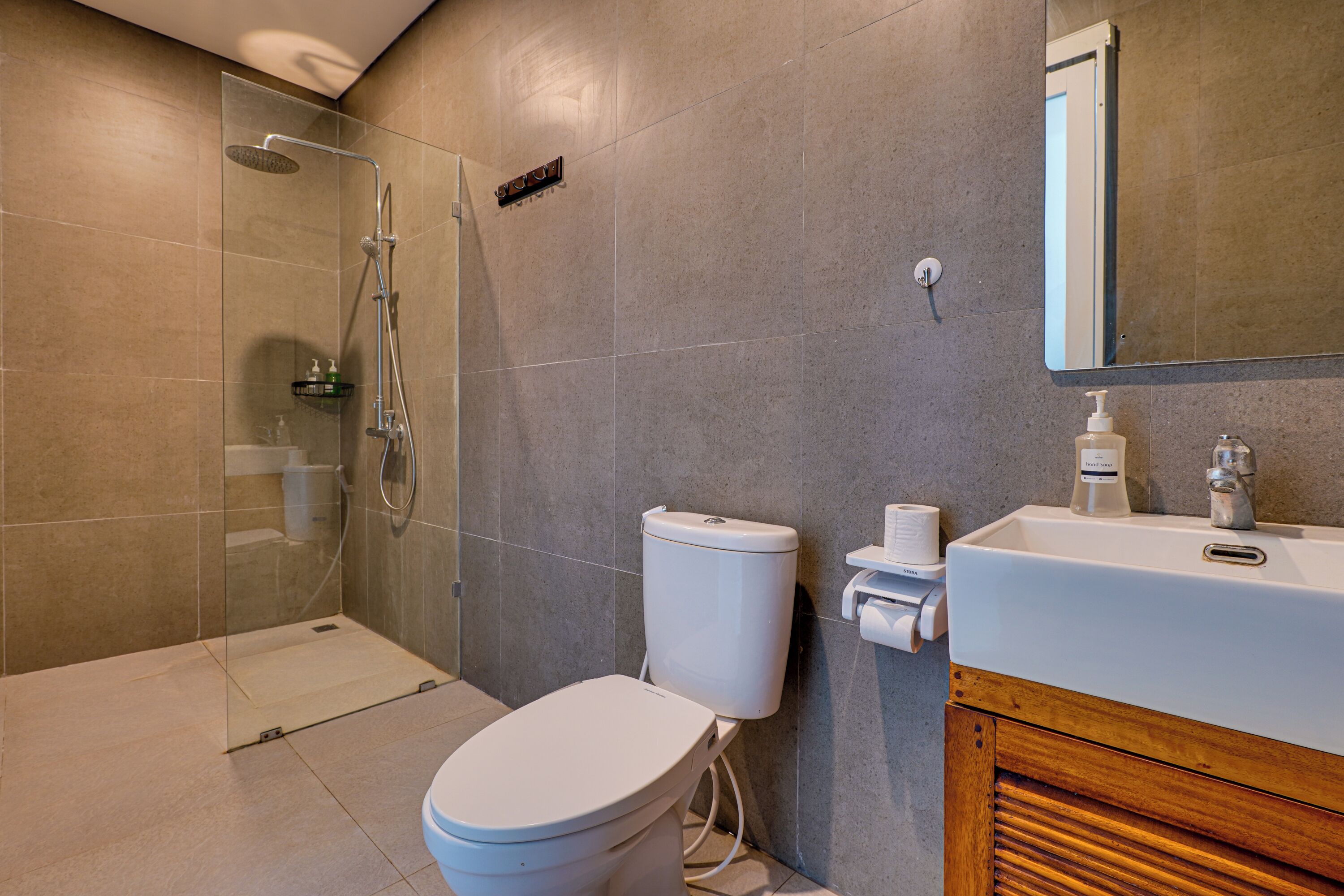 A modern bathroom with a glass-enclosed shower, a white toilet, and a wooden vanity with a sink.