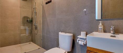 A modern bathroom with a glass-enclosed shower, a white toilet, and a wooden vanity with a sink.