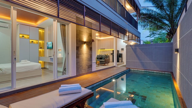 Habitación de hotel moderna con piscina, balcón y vistas al exterior.