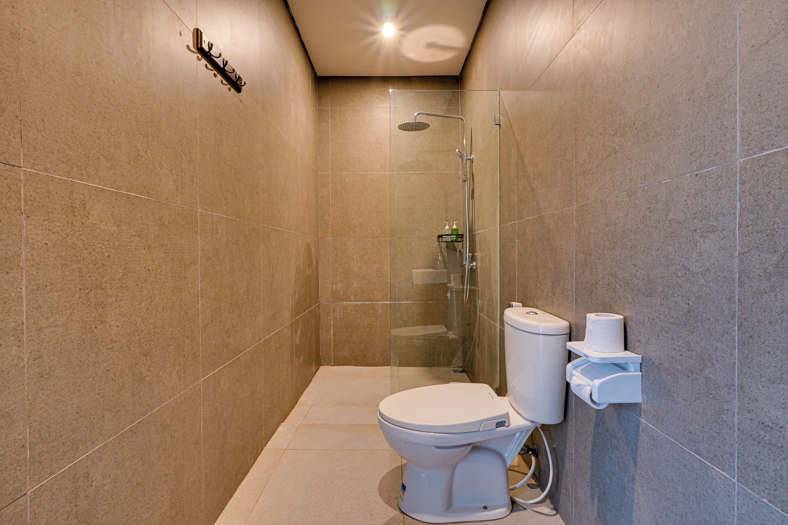 A modern bathroom with a toilet, shower, and hand dryer.