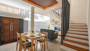 Una cocina moderna con armarios de madera, una mesa de comedor con sillas y una escalera con barandilla negra.
