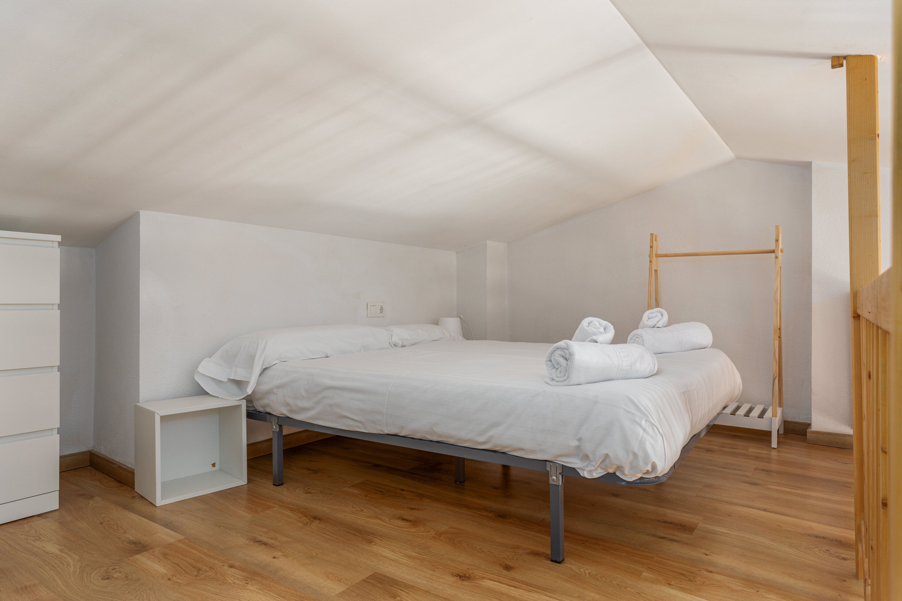 Ein Schlafzimmer mit einem Bett, einer hölzernen Bank und einer Klimmzugstange.