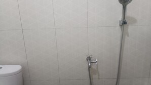Un bany amb dutxa, vàter i una paret amb un dibuix geom ètric.
