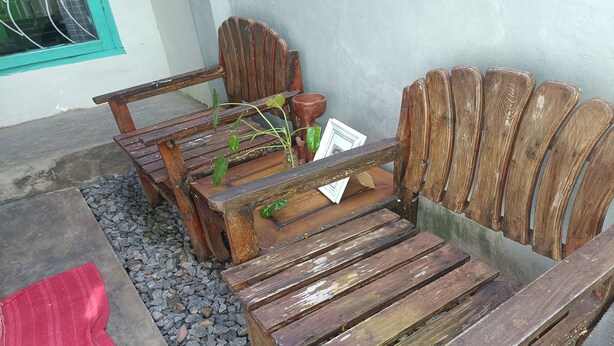 Un banc de fusta rústic amb respatller corbat i taula al davant.