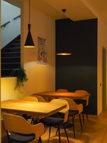 Un comedor moderno con una mesa y sillas de madera, una lámpara colgante negra y una escultura en la pared.