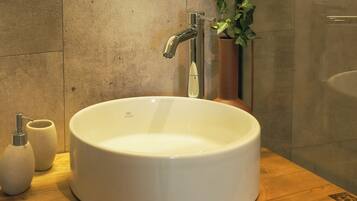 A bathroom with a white sink, a modern faucet, and a potted plant.