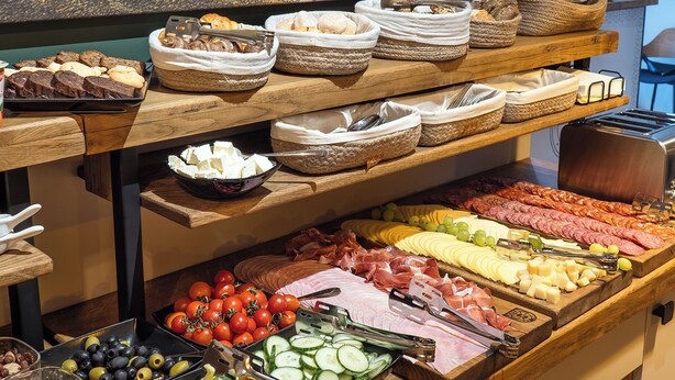 Buffet com diversos alimentos, incluindo carnes, queijos e vegetais.