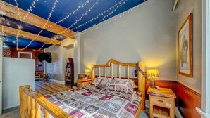 Ein gemütliches Schlafzimmer mit einem hölzernen Bett, einem Nachttisch und einem kleinen Tisch.