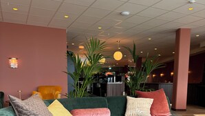 A modern lounge area with a green sectional sofa, multiple pillows, and a round wooden table. - Hotell Sillen (Lysekil)