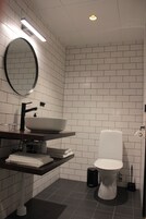 Un baño moderno con lavamanos, espejo y retrete blancos.