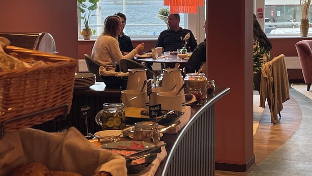 A restaurant with a view of the water, a buffet counter with food and drinks, and a casual seating area with chairs and tables. - Hotell Sillen (Lysekil)