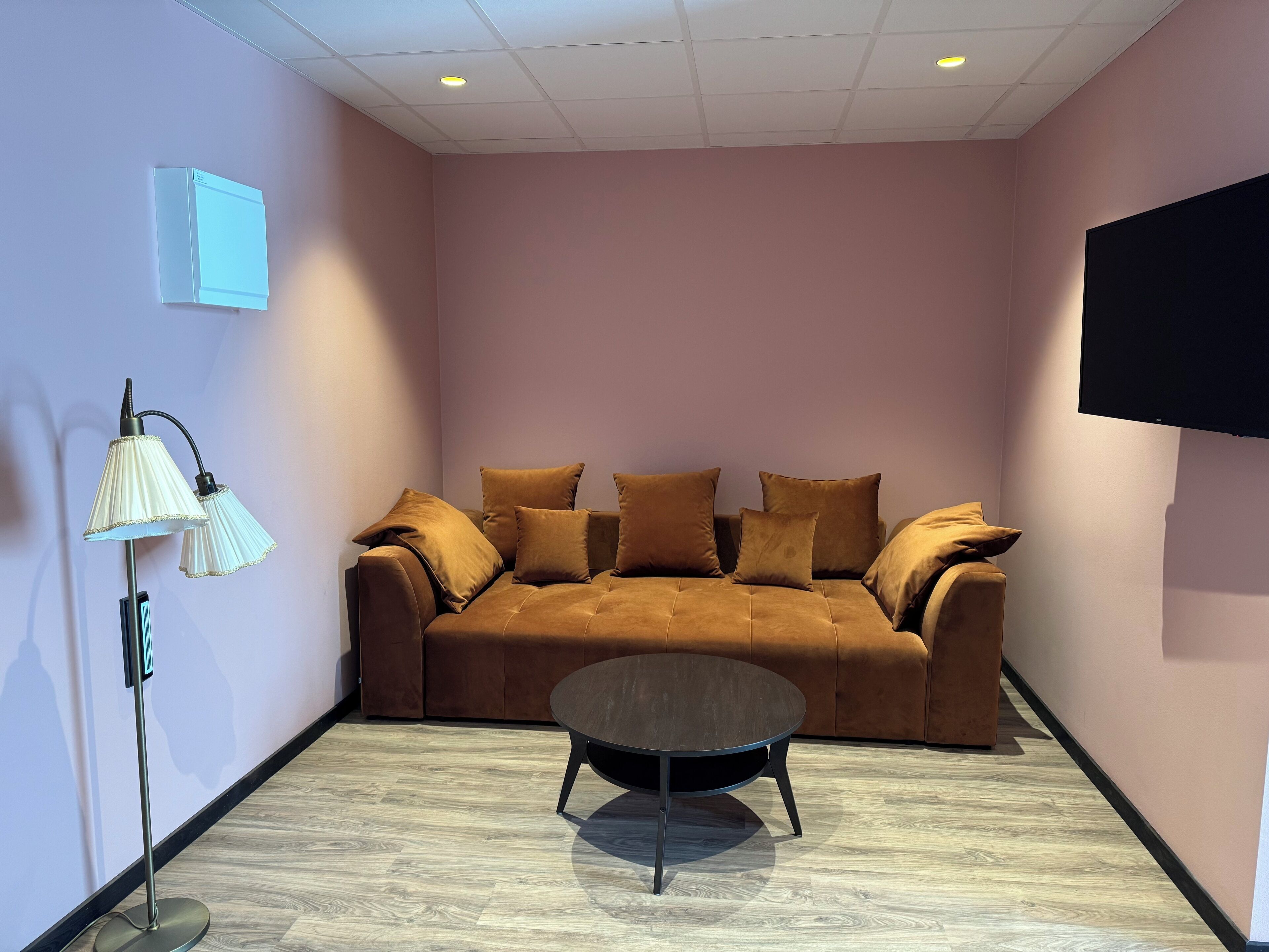 A modern living room with a brown sofa, a round coffee table, and a floor lamp.