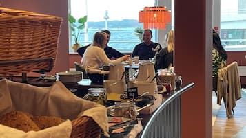 A buffet area with wicker baskets, a sign reading "In Lago Sill," and a view of the water outside.