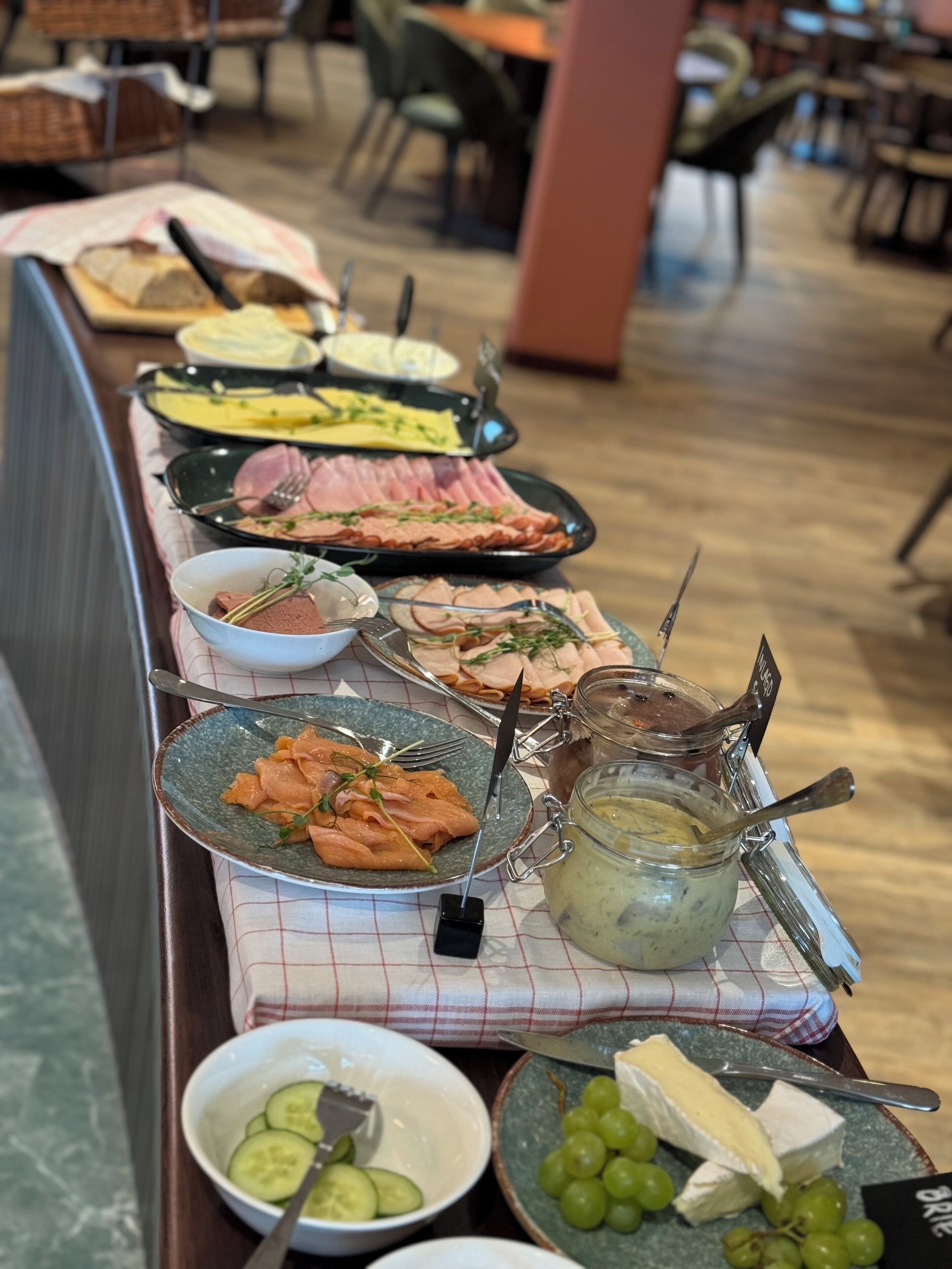 A buffet table with various food items including meats, cheeses, and fruits.