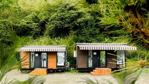Two small, modern cabins with wooden exteriors and striped roofs, set in a lush, green forested area. - Forest View Cottage 1 (森林景觀度假小屋1) (Jiaoxi Township)