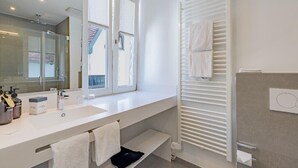 A modern bathroom with a large mirror, a white sink, and a towel rack. - Atlantic Grand Hotel - Appartement (Lübeck)