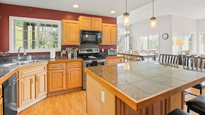 A spacious kitchen with wooden cabinets, granite countertops, and a large island.