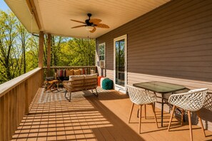Eine überdachte Terrasse im Freien mit Deckenventilator, einer Couch, einem Tisch und Stühlen.