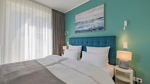 A hotel room with a large bed, a blue headboard, white bedding, a painting on the wall, and a nightstand with a lamp. - Atlantic Grand Hotel - Appartement Plus mit Balkon Oder Veranda (Lübeck)
